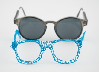 Glasses made with a 3d pen and sunglasses on a white background.