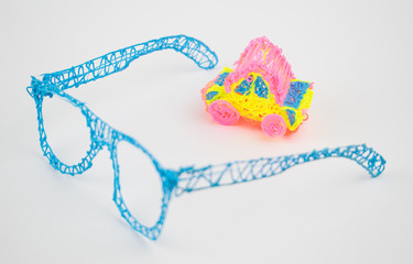 Glasses made with a 3d pen and a toy car on a white background.