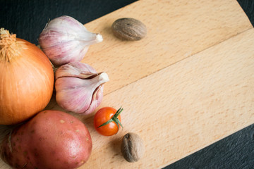 Onion, garlic, tomato and potatoes on a wooden background.