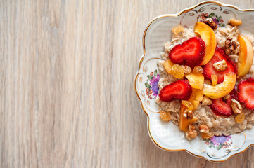 Breakfast from porridge and pieces of fresh juicy fruit