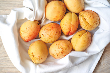 Apricots in human hands on light fabric