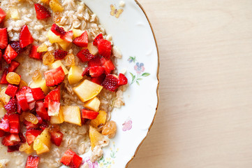 Breakfast from porridge and pieces of fresh juicy fruit
