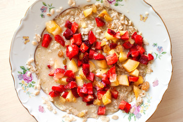 Breakfast from porridge and pieces of fresh juicy fruit