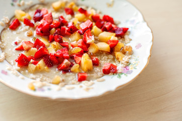 Breakfast from porridge and pieces of fresh juicy fruit
