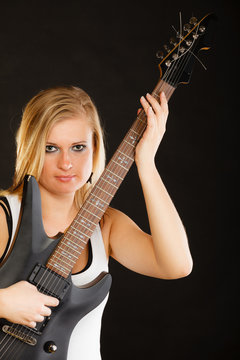 Blonde woman holding electric guitar, black background