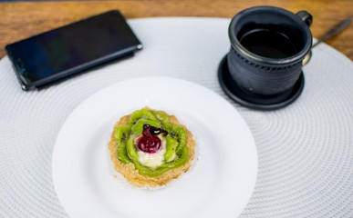 A cake, a cup of coffee and a phone.