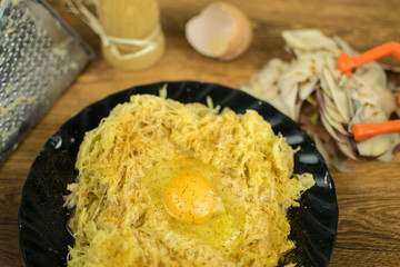Grated potatoes on a grater with a chicken egg.
