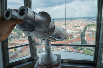 Hand holding tourist Binocular and blurred city on background in the high view point