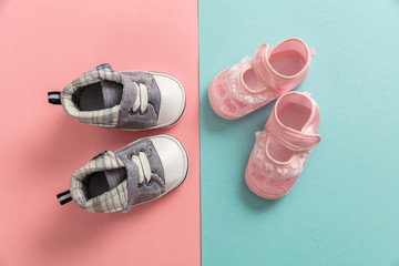 Baby boy and girl shoes on pastel colors background