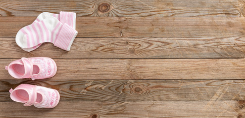 Baby girl shoes and socks on wooden background