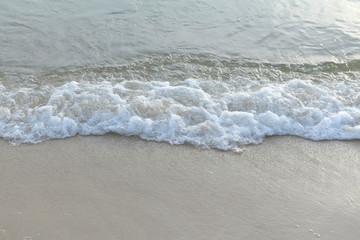 The sea with waves hit the sandy beach in the morning, with copy space text