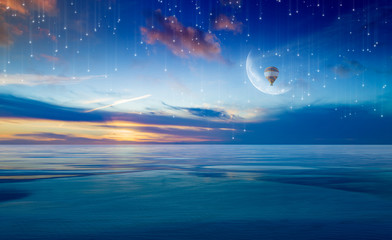 Colorful hot air balloon in sunrise sky with crescent above serene sea