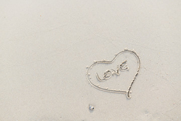 Heart and Love written on the beach by the sea in the morning