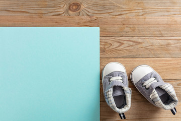 Baby boy shoes on pastel blue and wooden background