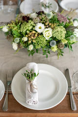 Neatly twisted into a tube dining room napkin decorated with a sprig of pistachio. Wedding Banquet or gala dinner. The chairs and table for guests, served with cutlery and crockery. party on terrace