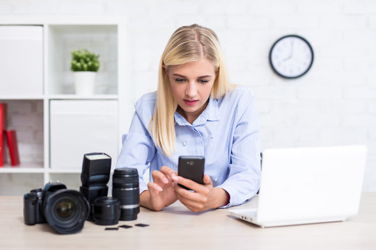 female photographer with camera, computer, smart phone and photography equipment in office
