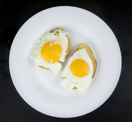 Two sandwiches with egg on a white plate.