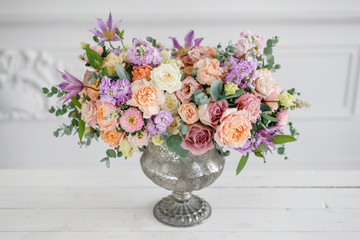 Gorgeous bouquet of different flowers. floral arrangement in vintage metal vase. table setting. lilac and peach color