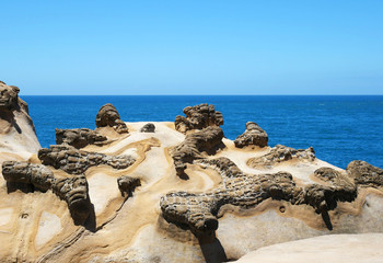 Fototapeta na wymiar Ginger rock landscape in Yehliu Geopark, New Taipei, Taiwan. The interlacing patterns as shown on the surface of ginger rock are the result of crust extrusion occurred underground.