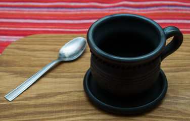 Black clay cup with saucer and spoon.