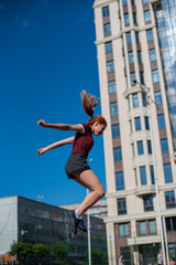 the red-haired student in shorts gives the standards for jumping at the physical education class on an open sports ground. girl doing crossfit exercises outdoor. red-haired young woman is jumping
