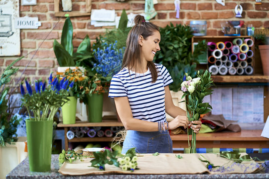 Picture of smiling florist putting together flowers for a bouquet