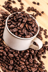 a Cup of coffee full of coffee beans on wood background, side view