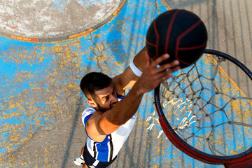 Street basketball player performing power slum dunk.