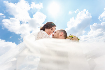 loving couple of newlyweds walks in the city with a bouquet of roses and a veil flying in the wind
