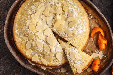 Almond cake on dark dish, top view, dark background.