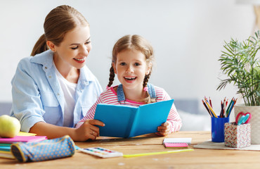 mother and child daughter doing homework writing and reading at home.
