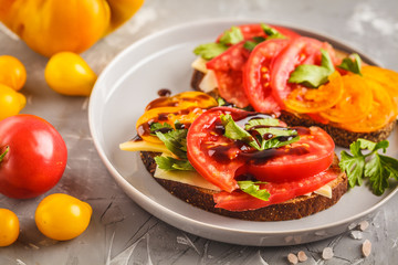 Sandwiches with tomatoes and cheese on gray plate, top view.