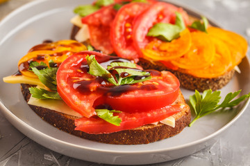 Sandwiches with tomatoes and cheese on gray plate, top view.