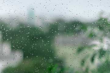 Drops of water on a window glass with a green blurred background.