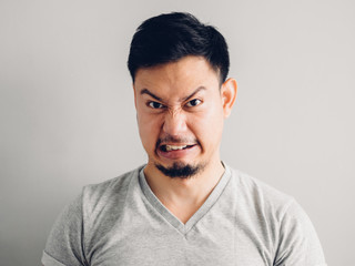 Headshot photo of Asian man with hate and disgusting face. on grey background.