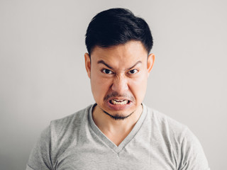 Headshot photo of Asian man with angry and furious face. on grey background.