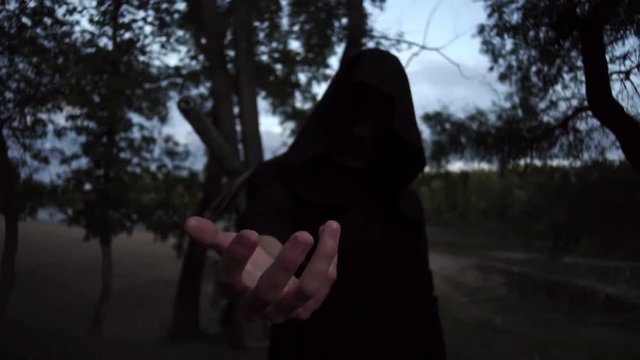 mysterious witcher in a cloak holding a fire man in fantasy medieval dress. Halloween