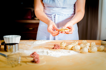 Obraz na płótnie Canvas woman makes dumplings at home on kitchen table, close up