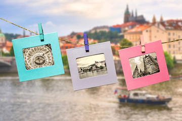 Fototapeta na wymiar Old photos of the main landmark of Prague in a fun framework, attached with a clothes-peg clothespin to the hanging lashing rope against the backdrop of the panorama of Prague. 