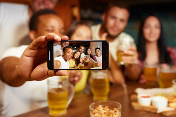 Group of funny friends taking self portrait in bar.