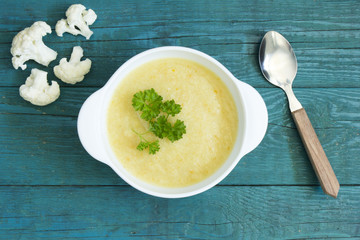 Creamy cauliflower soup with parsley,on a blue kitchen table 