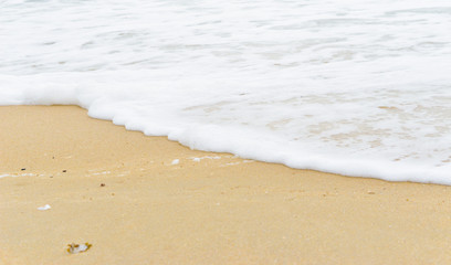 Fototapeta na wymiar Soft wave foam on sandy beach