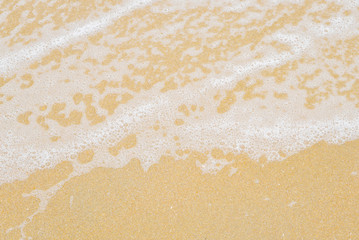 Soft wave foam on sandy beach