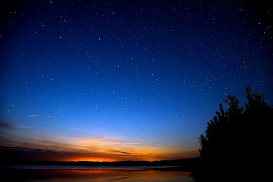 Amazing colorful sky after sunset by the river. Sunset and night sky with a lot of shiny stars.