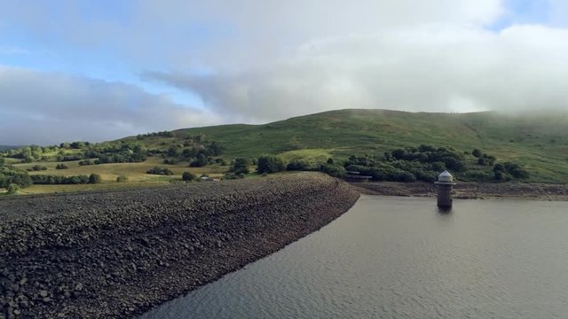 Aerial view, forward side move. Drone panorama of Llyn Celyn water reservoir with dam and green fields in Wales