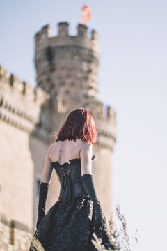 Pretty red haired medieval girl poses together castle.