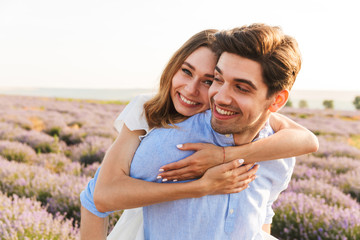 Joyful young couple having fun at the lavender field together