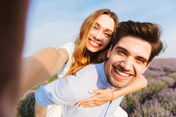 Happy young couple taking a selfie at the lavender field