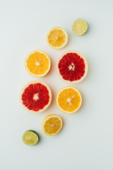 top view of grapefruit, lemon, lime and orange slices, on grey