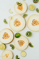 top view of melon, lime and kiwi slices, on grey background